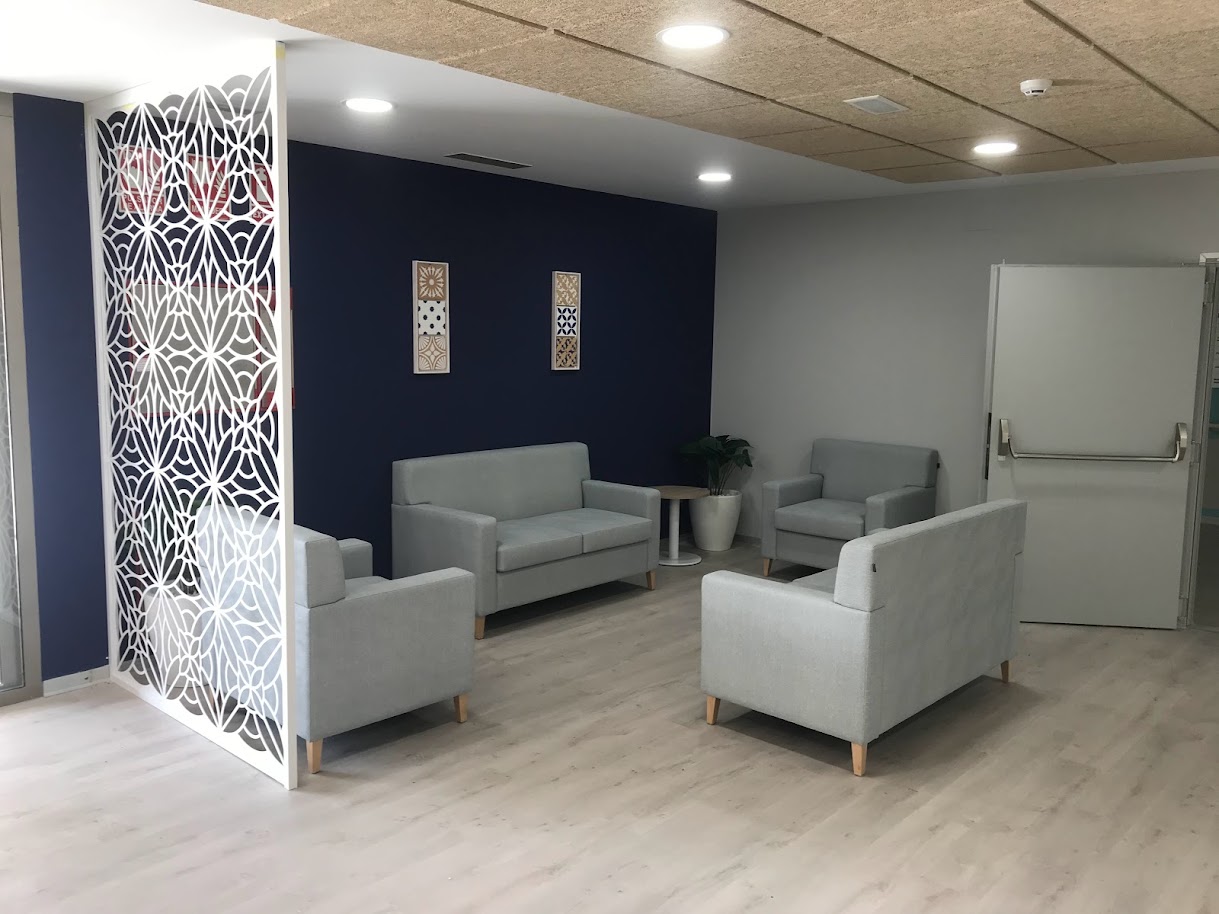 Sala de espera moderna y acogedora con dos sofás y dos sillones grises